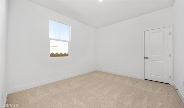 spare room with light carpet and baseboards