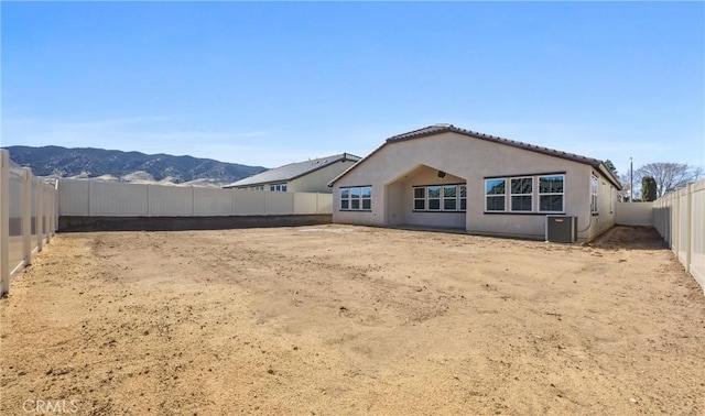 back of property featuring a fenced backyard, a mountain view, cooling unit, and stucco siding