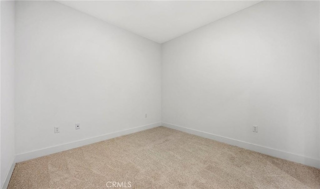 unfurnished room featuring light carpet and baseboards