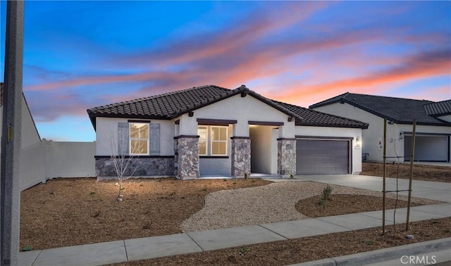 view of front of house with a tile roof, stucco siding, a garage, stone siding, and driveway