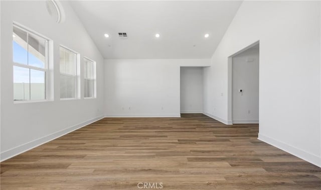 empty room featuring lofted ceiling, baseboards, wood finished floors, and recessed lighting