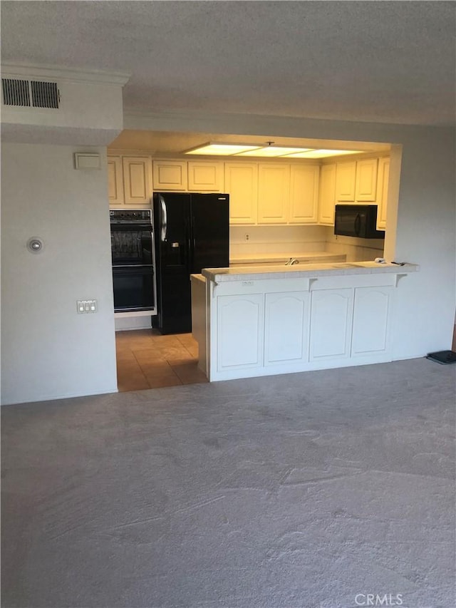 kitchen with kitchen peninsula, a textured ceiling, light colored carpet, black appliances, and white cabinetry