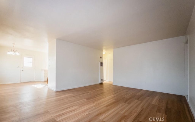 unfurnished room with light wood-type flooring and a chandelier