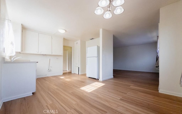 unfurnished living room featuring a chandelier, light hardwood / wood-style floors, and sink