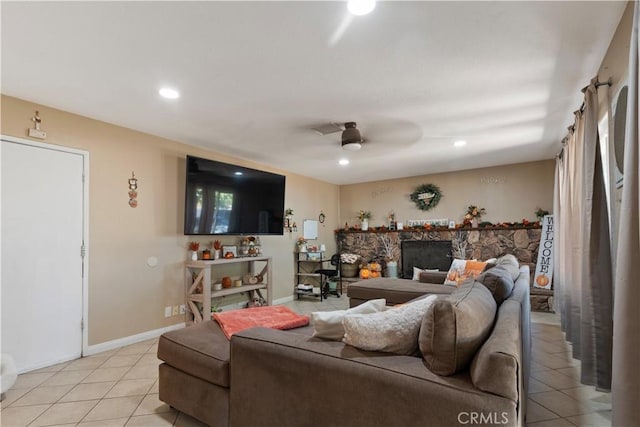 tiled living room with ceiling fan and a fireplace