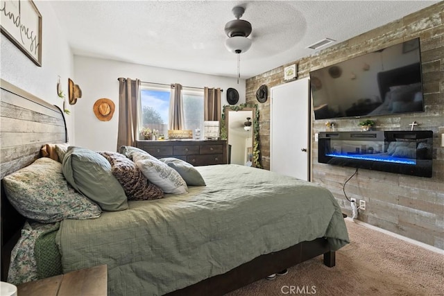 carpeted bedroom with a textured ceiling, ceiling fan, and brick wall