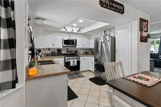 kitchen with white cabinets, appliances with stainless steel finishes, light stone counters, and sink