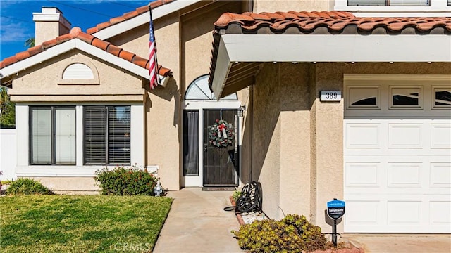 view of exterior entry with a garage and a yard