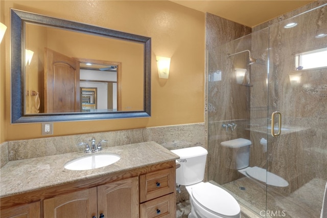 bathroom with an enclosed shower, vanity, and toilet