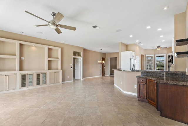 kitchen with ceiling fan with notable chandelier, sink, decorative light fixtures, built in features, and light tile patterned flooring