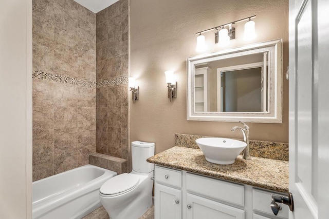 full bathroom featuring tiled shower / bath, vanity, and toilet