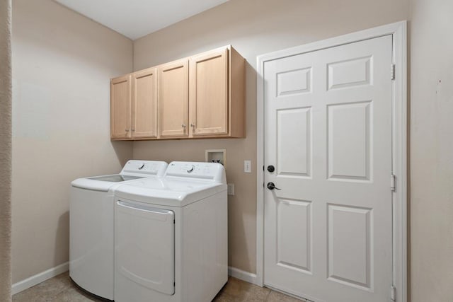 laundry area featuring washer and clothes dryer, light tile patterned floors, and cabinets