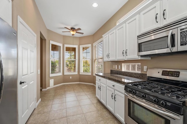 kitchen featuring white cabinets, appliances with stainless steel finishes, light tile patterned floors, and dark stone countertops