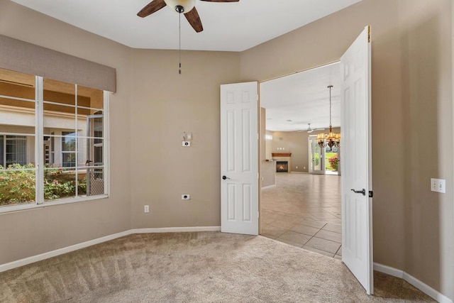 carpeted spare room with plenty of natural light and ceiling fan with notable chandelier