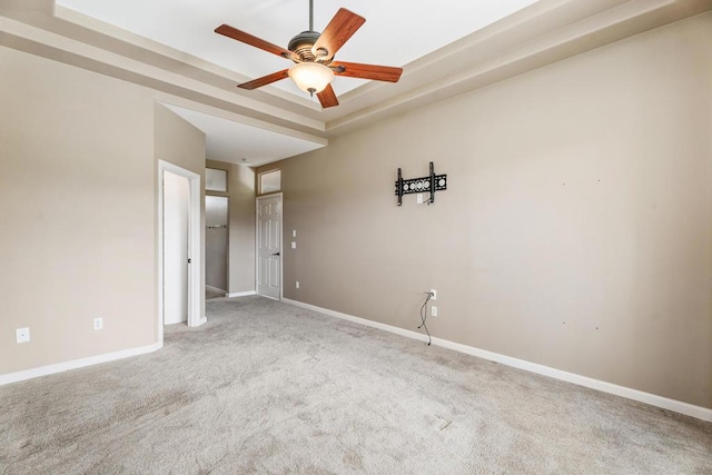 unfurnished room featuring carpet flooring, a raised ceiling, and ceiling fan