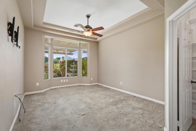 carpeted spare room with ceiling fan and a tray ceiling