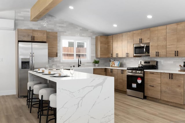 kitchen with lofted ceiling with beams, a kitchen breakfast bar, an AC wall unit, light wood-type flooring, and appliances with stainless steel finishes