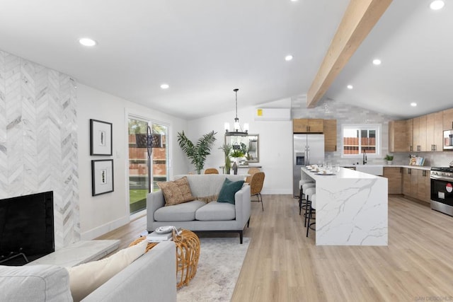 living room with a chandelier, lofted ceiling with beams, light hardwood / wood-style flooring, and sink