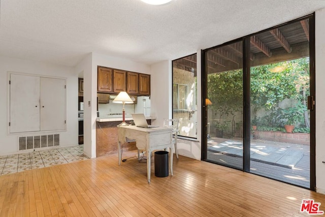 unfurnished office featuring light hardwood / wood-style flooring and a textured ceiling