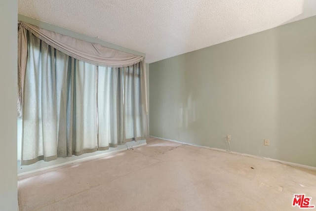 empty room with a textured ceiling and light carpet