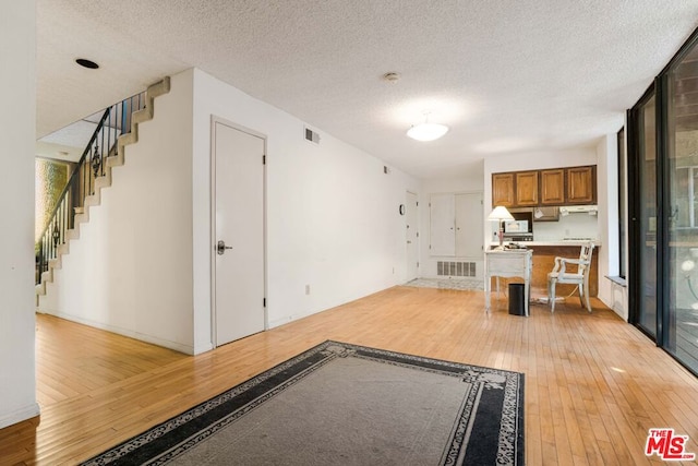 unfurnished living room with light wood-type flooring and a textured ceiling