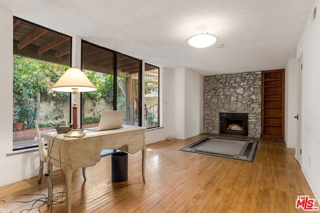 interior space with a fireplace, wood-type flooring, a textured ceiling, and a healthy amount of sunlight