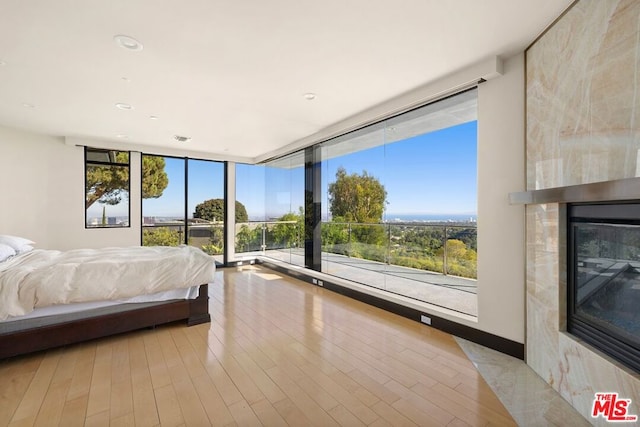 unfurnished bedroom featuring multiple windows, a premium fireplace, expansive windows, and light hardwood / wood-style floors