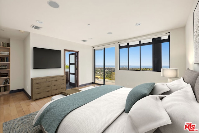 bedroom featuring access to exterior, multiple windows, and light hardwood / wood-style flooring