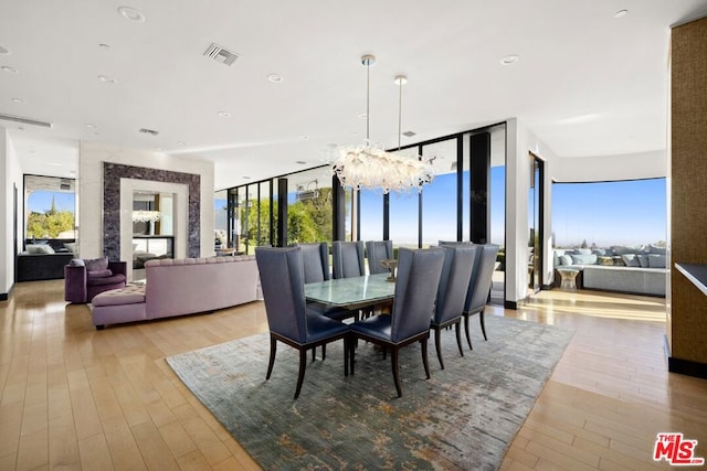 dining space with light hardwood / wood-style floors, an inviting chandelier, and floor to ceiling windows