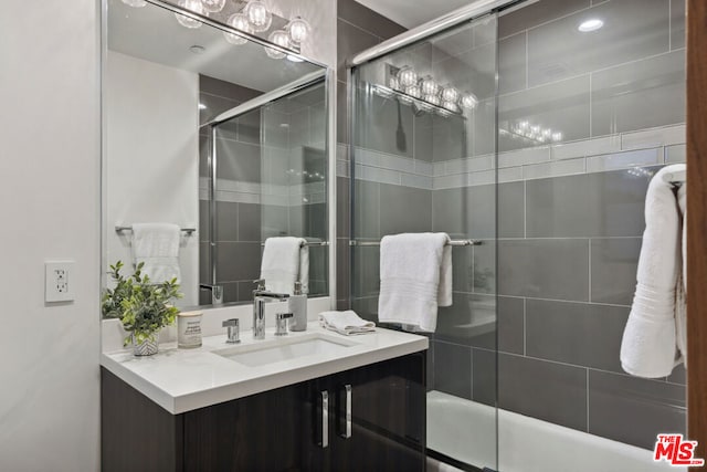 bathroom featuring combined bath / shower with glass door and vanity