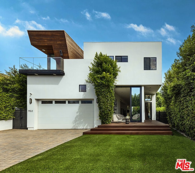 contemporary home with a front lawn, a balcony, and a garage