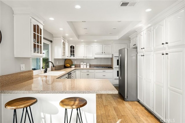 kitchen with kitchen peninsula, appliances with stainless steel finishes, a breakfast bar area, and sink