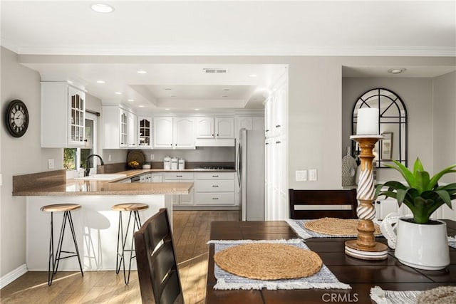 kitchen with kitchen peninsula, stainless steel appliances, sink, white cabinets, and hardwood / wood-style floors