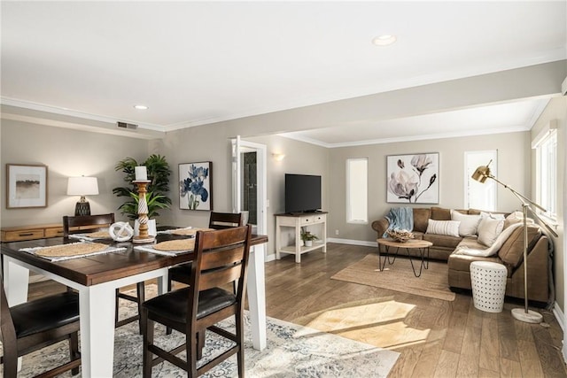 dining room with hardwood / wood-style flooring and crown molding