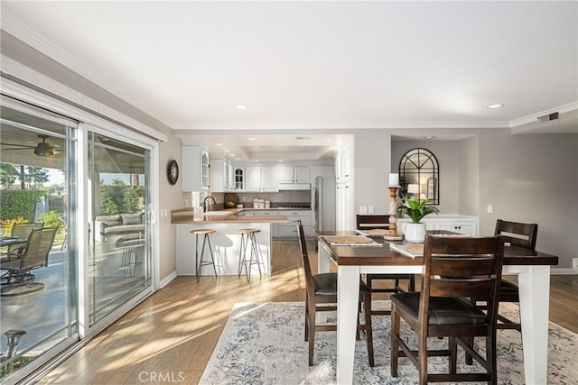 dining space featuring light hardwood / wood-style floors, crown molding, and sink