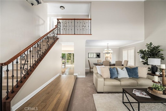 living room featuring a high ceiling, hardwood / wood-style flooring, an inviting chandelier, and ornamental molding