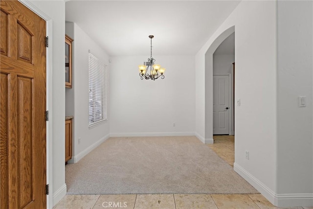 carpeted empty room with a chandelier