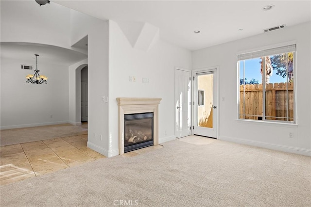 unfurnished living room featuring light colored carpet and an inviting chandelier