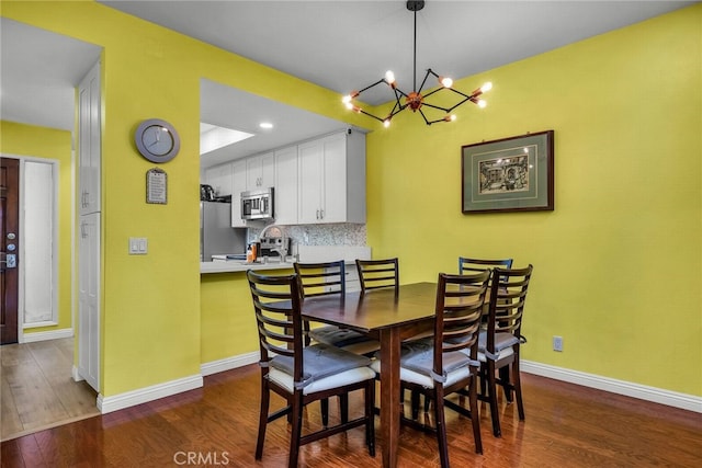 dining area with dark hardwood / wood-style floors and a notable chandelier