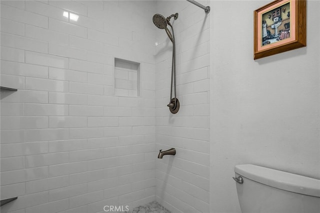 bathroom featuring a tile shower and toilet