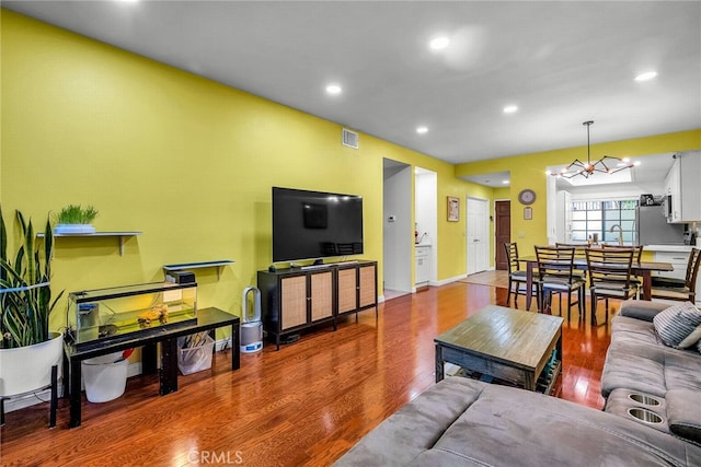 living room featuring wood-type flooring and an inviting chandelier