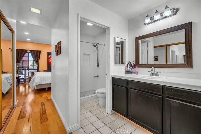 bathroom featuring a tile shower, vanity, hardwood / wood-style flooring, and toilet