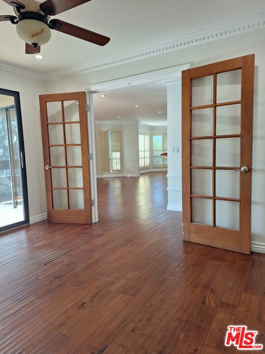 unfurnished room with ceiling fan, french doors, dark hardwood / wood-style floors, and ornamental molding