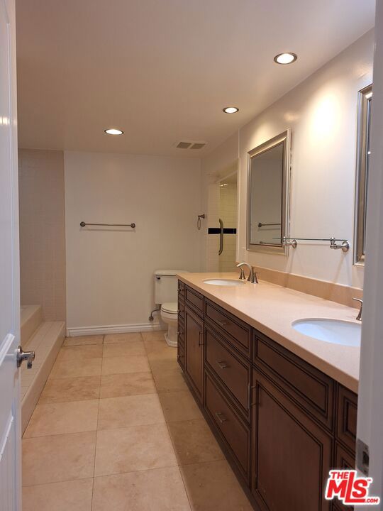 bathroom with toilet, vanity, and tile patterned flooring