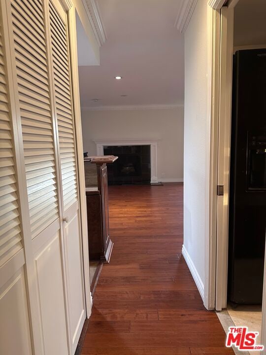 corridor with dark wood-type flooring and ornamental molding