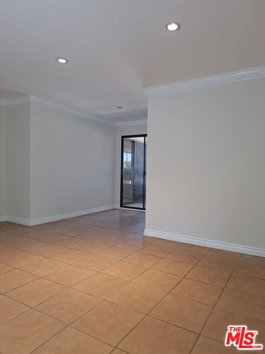 tiled empty room featuring crown molding