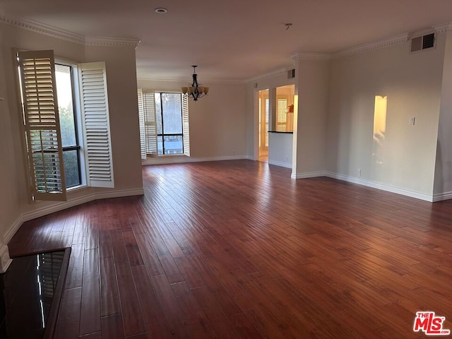 empty room with dark hardwood / wood-style flooring, crown molding, and a notable chandelier