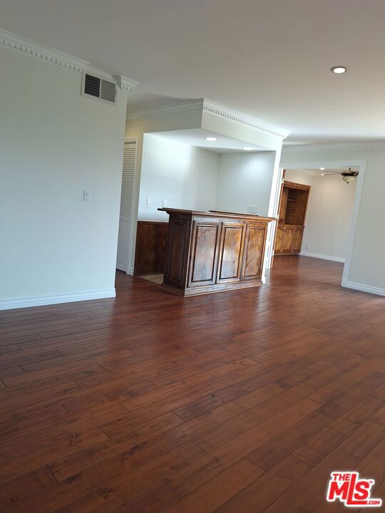 spare room with dark hardwood / wood-style flooring and crown molding