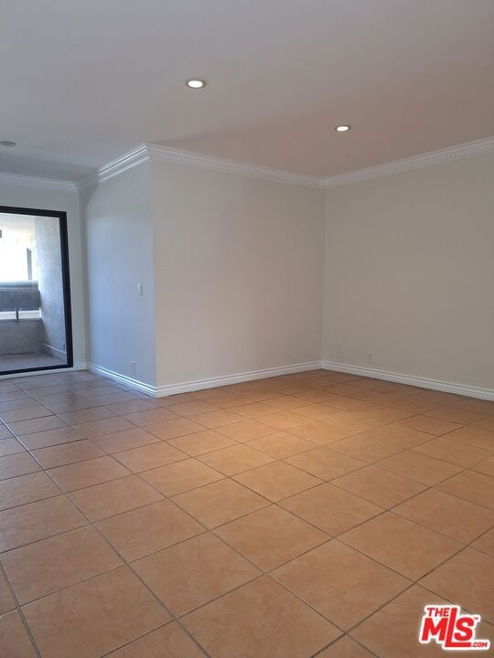 tiled spare room featuring ornamental molding