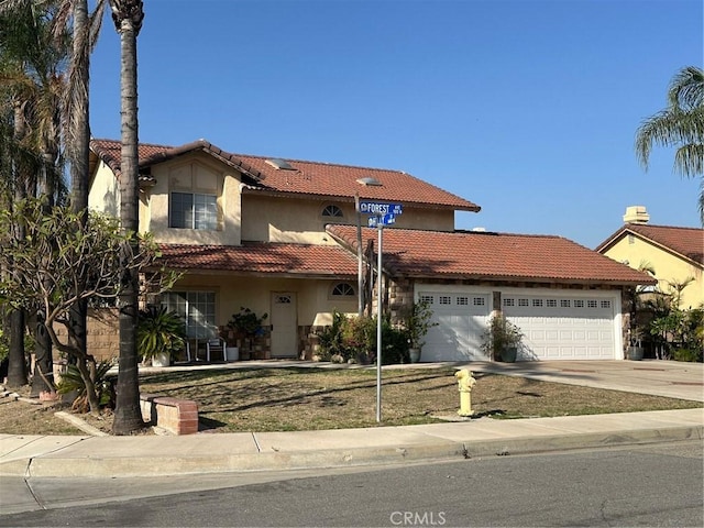 mediterranean / spanish-style house with a garage, a tiled roof, concrete driveway, and stucco siding